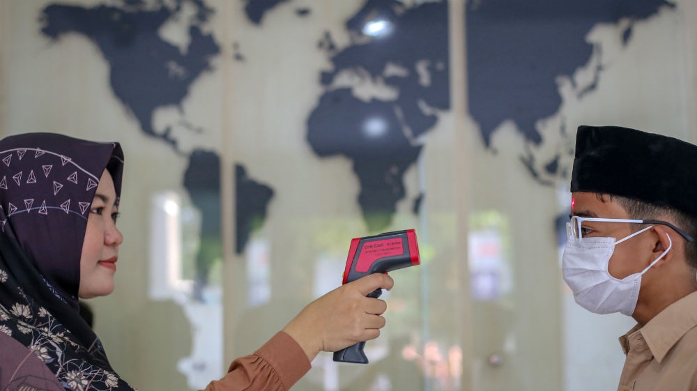 A teacher checks a student with a thermometer at school after Indonesia confirmed new cases of coronavirus disease (COVID-19), in Jakarta, Indonesia, March 11, 2020 in this photo tak