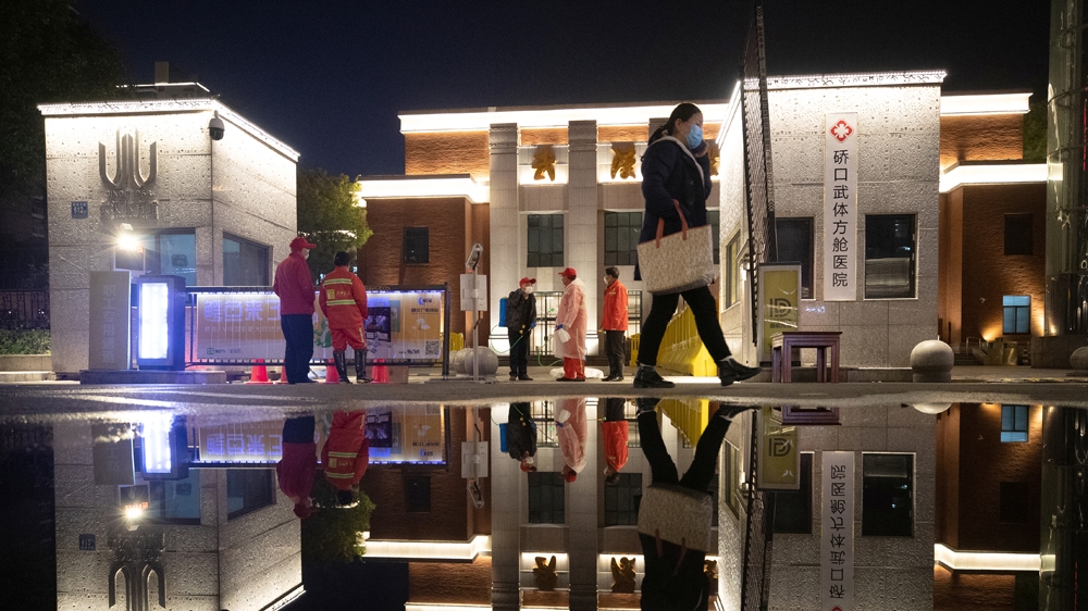 Workers wearing face masks are seen in front of a makeshift hospital that is closed following its last group of patients of the novel coronavirus have been discharged, i