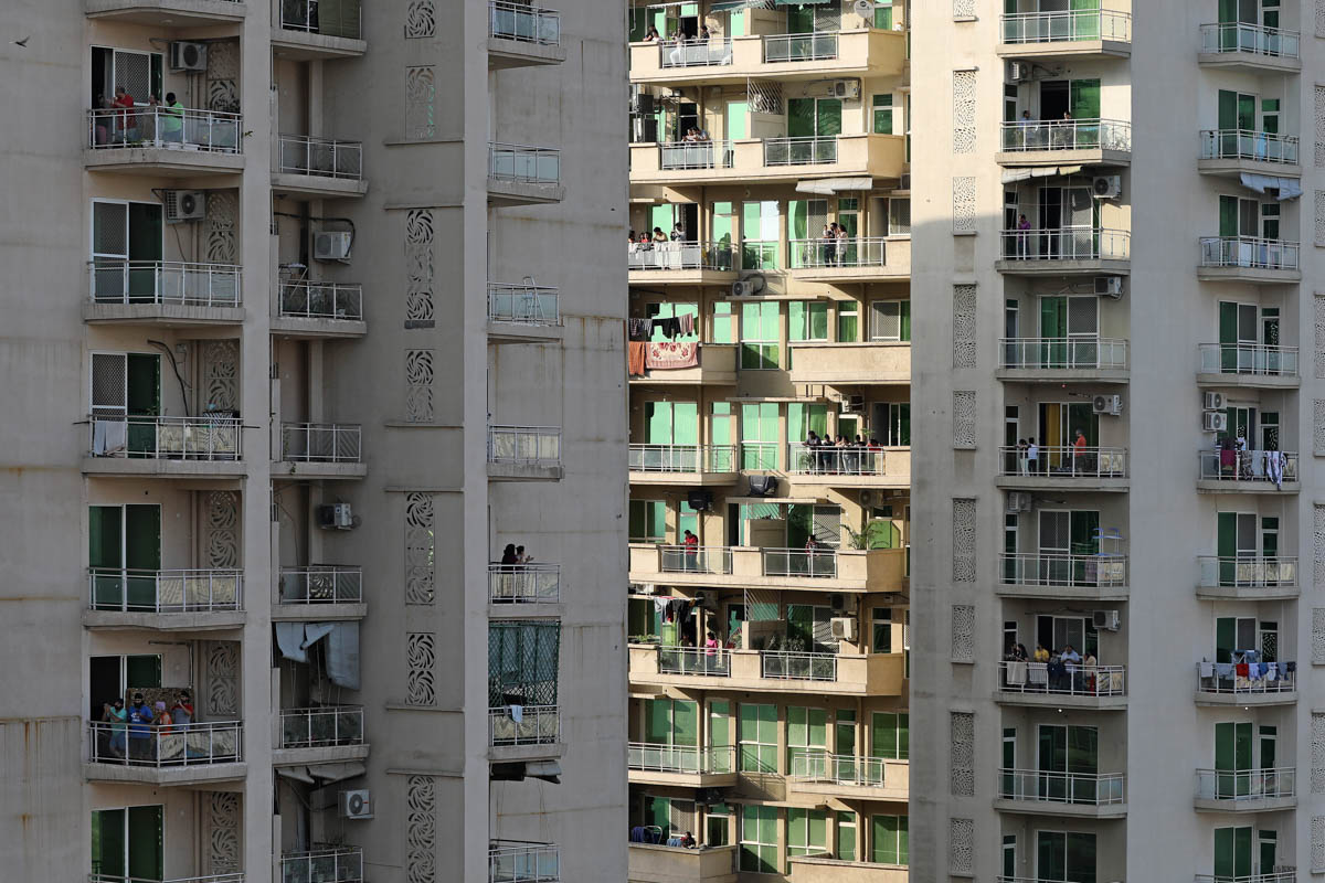 People, in a residential complex, clap and bang utensils from their balconies in show of appreciation to health care workers in Greater Noida, a suburb of New Delhi, India, Sunday, March 22, 2020. Ind