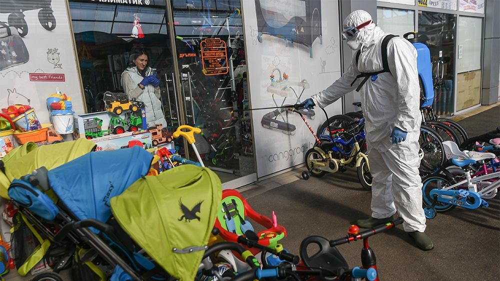A store vendor takes photos of a member of Sofia's Municipality disinfecting the outside of her store in the biggest market for Chinese goods in Sofia, Bulgaria to prevent the spread of the COVID-19, 