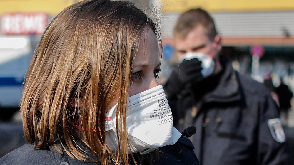 Police officers wear face masks as they surround a spontaneous rally in Berlin's Kreuzberg district on March 28, 2020, amid the novel coronavirus Covid-19 pandemic. (Photo by David GANNON / AFP)