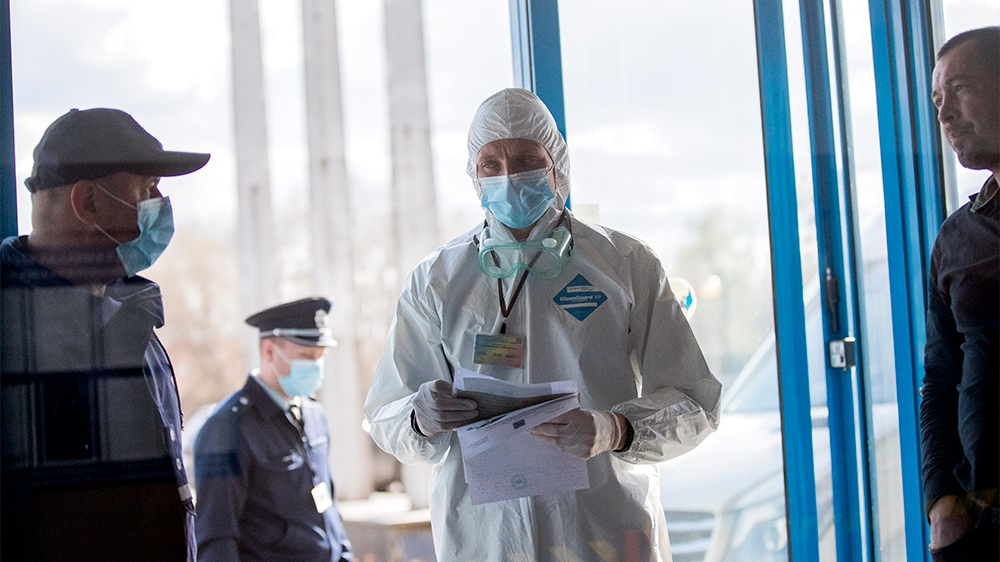 epa08294434 Customs officers wear protective masks as they control the cars of passengers arriving at the Leuseni Custom, Moldova, 14 March 2020. Moldova closes some border crossings with Romania aft
