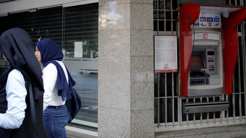Two women walk past a closed bank office in Beirut, Lebano