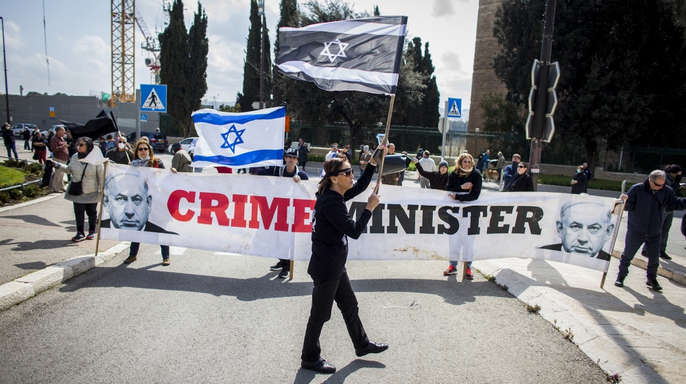 People wave Israeli flags during a protest outside the Israeli parliament in Jerusalem, Thursday, March 19, 2020. Hundreds of people defied restrictions on large gatherings to protest outside parliame
