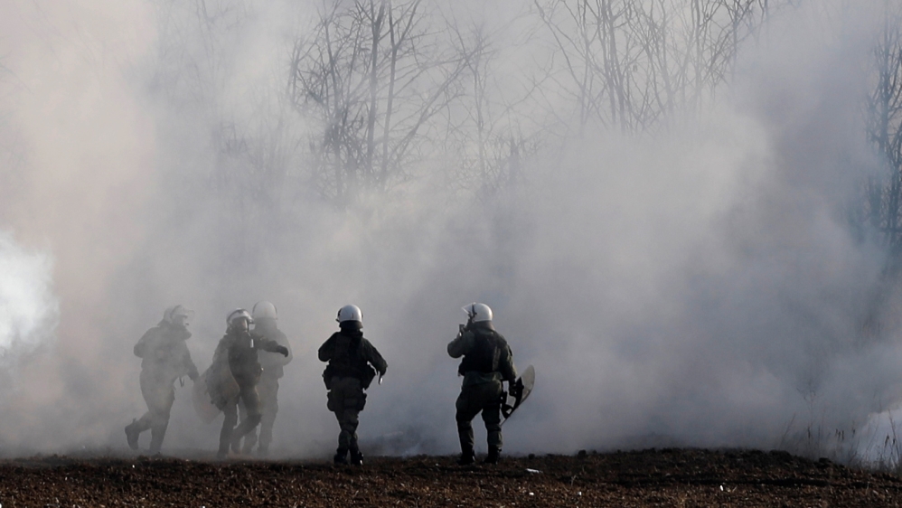 Greek riot police officers walk amid clouds of tear gas near Turkey''s Pazarkule border crossing, in Kastanies