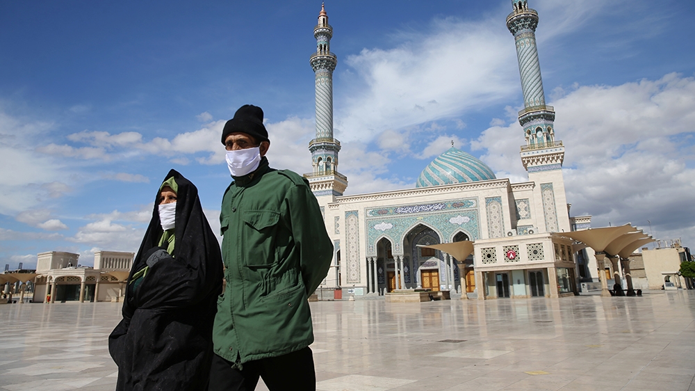 A couple wearing protective face masks, following the outbreak of coronavirus disease (COVID-19), walks on the street in Qom, Iran March 24, 2020. Picture taken March 24, 2020. WANA (West Asia News Ag