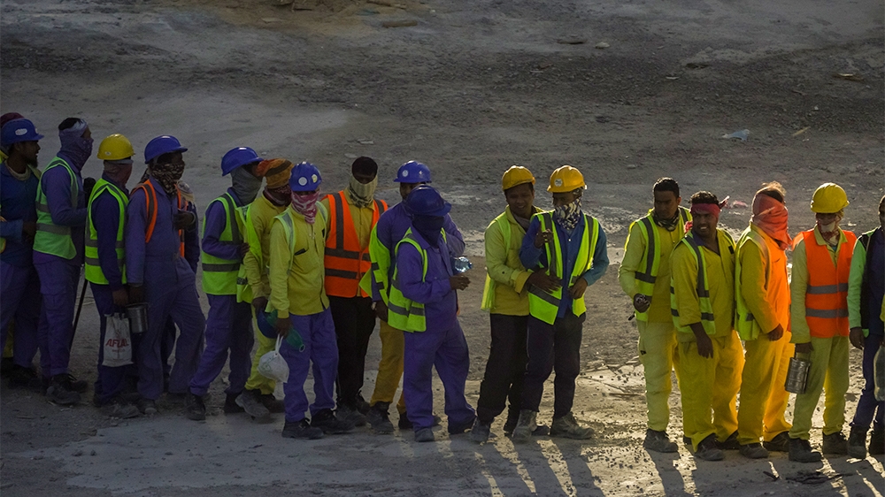 Construction workers queuing to board a bus as their finished their shift on a construction site in Doha, Qatar, March 29, 2020 [Sorin Furcoi/Al Jazeera]