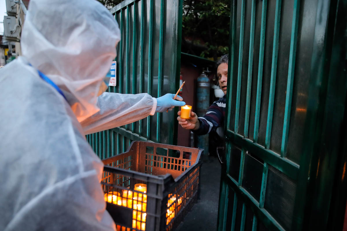A volunteer wearing a protective outfit distributes holy light in Bucharest, Romania, Saturday, April 18, 2020. Priests accompanied by volunteers distributed the holy light ahead of the usual time, at