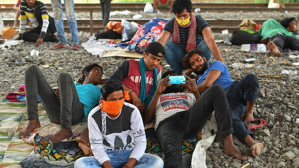 Migrant labourers watch a movie on their mobile phone while resting under a bridge during a government-imposed nationwide lockdown as a preventive measure against the spread of the COVID-19 coronaviru