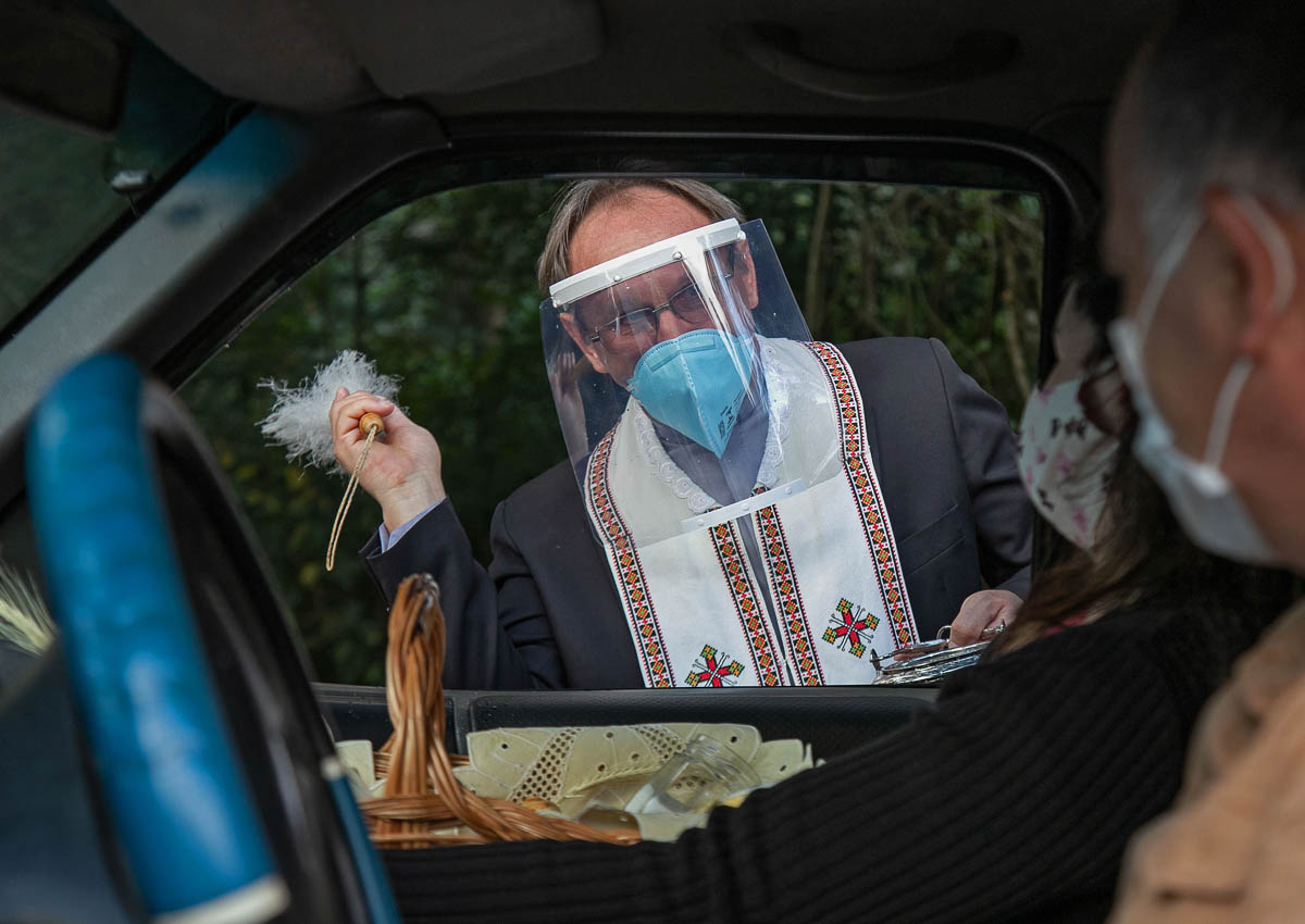 Ukranian descendant priest Elias Marinhuk wears a face mask and shield against the spread of the new coronavirus as he blesses Easter baskets carried by Catholic faithful on their cars in Curitiba, Pa