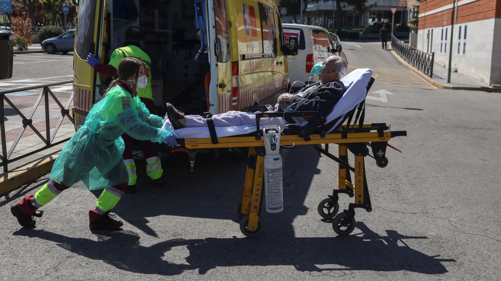 A healthcare worker wearing a protective face mask and suit transports a patient from an ambulance to the emergency unit at 12 de Octubre hospital during the coronavirus disease (COVID-19) outbreak in