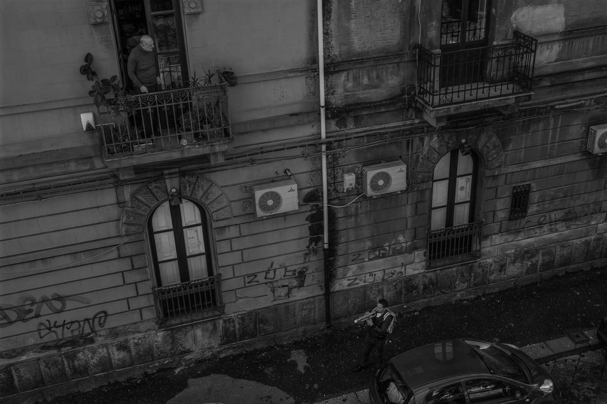 Michele, a trumpeter, plays in the city streets alleviating the quarantine of people with his music. The streets are empty but the people often stand in the balcony to take some air or to sing togethe