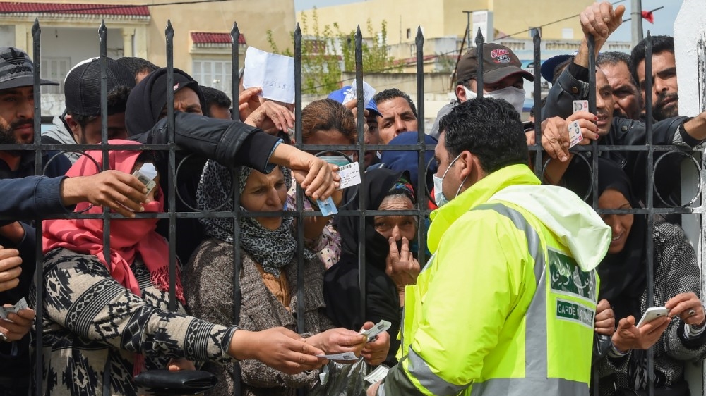 Impoverished Tunisian citizens gather with their identification cards in front of the headquarters of Mnihla delegation, in Ariana