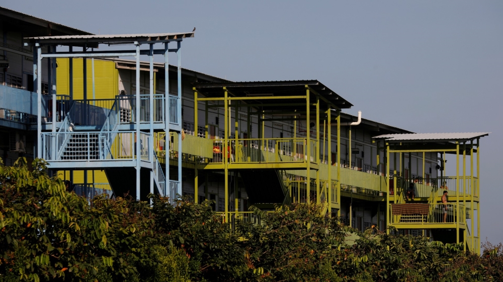 Migrant workers sit outside their rooms at a dormitory declared as an isolation area in Singapore