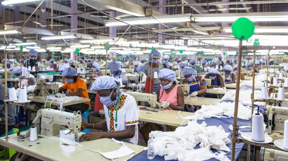 Workers use sewing machines to assemble a piece of personal protective equipment for COVID-19 coronavirus frontline health workers at a factory commissioned by the government, in Accra