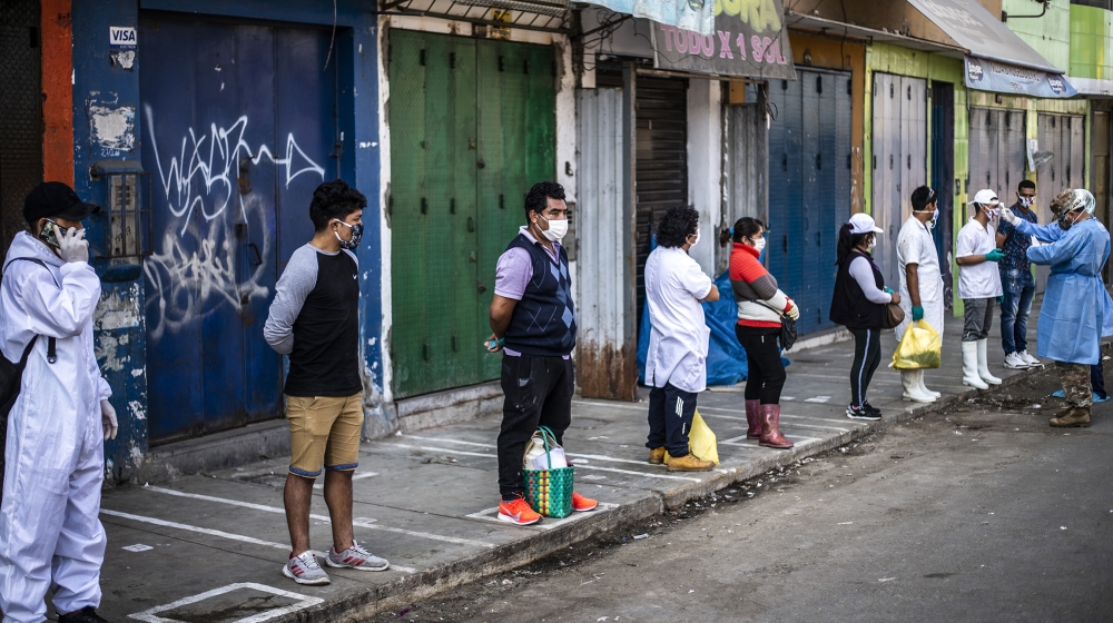 Employees of the Ciudad de Dios market wait respecting safety distances to be tested by workers of the Health Ministry to discard COVID-19 in Lima on May 11, 2020. ERNESTO BENAVIDES / AFP