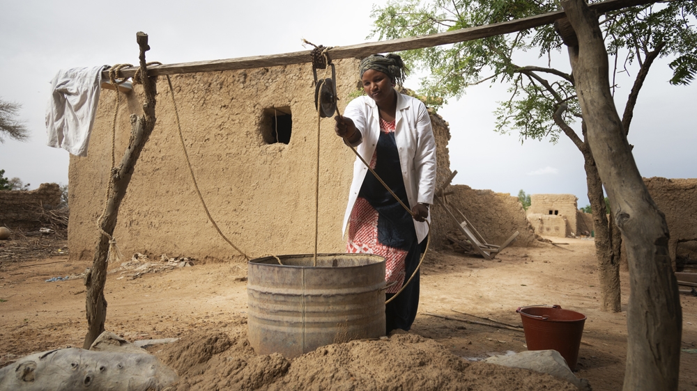 Salimata Dagnogo, 32, Matron of Talo Health Centre, collects dirty water from an open well in the village. Salimata has worked at Talo for eight years and faces big challenges in her role without the