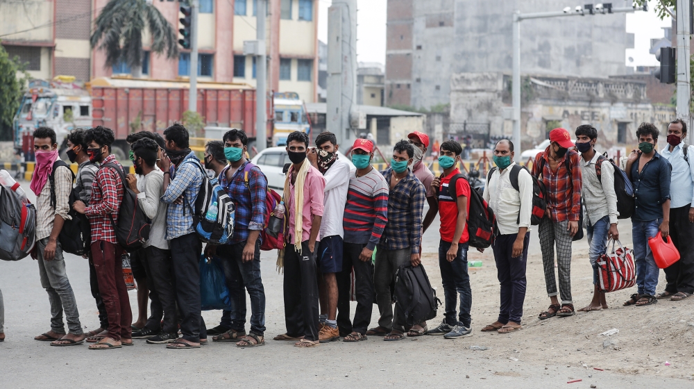 Migrant workers who arrived from neighboring Maharashtra state line up to board a truck as they are transported to a quarantine center in Prayagraj, Uttar Pradesh state, India, Sunday, May 10, 2020. I