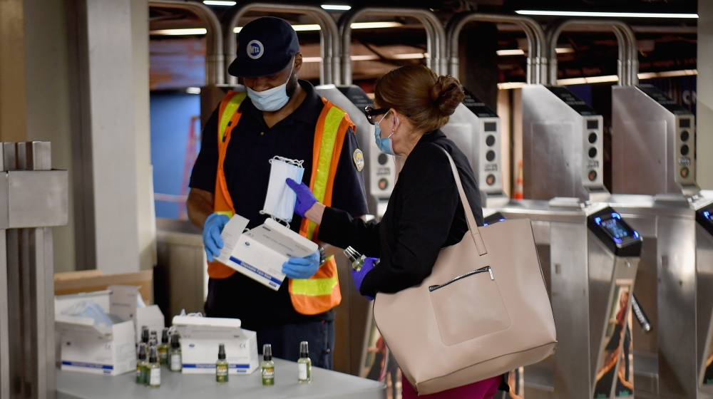 An MTA worker hands out free hand sanitizer and face masks at the Grand Central Station subway during morning rush hour on June 8, 2020 in New York City. Today New York City enters "Phase 1" of a four