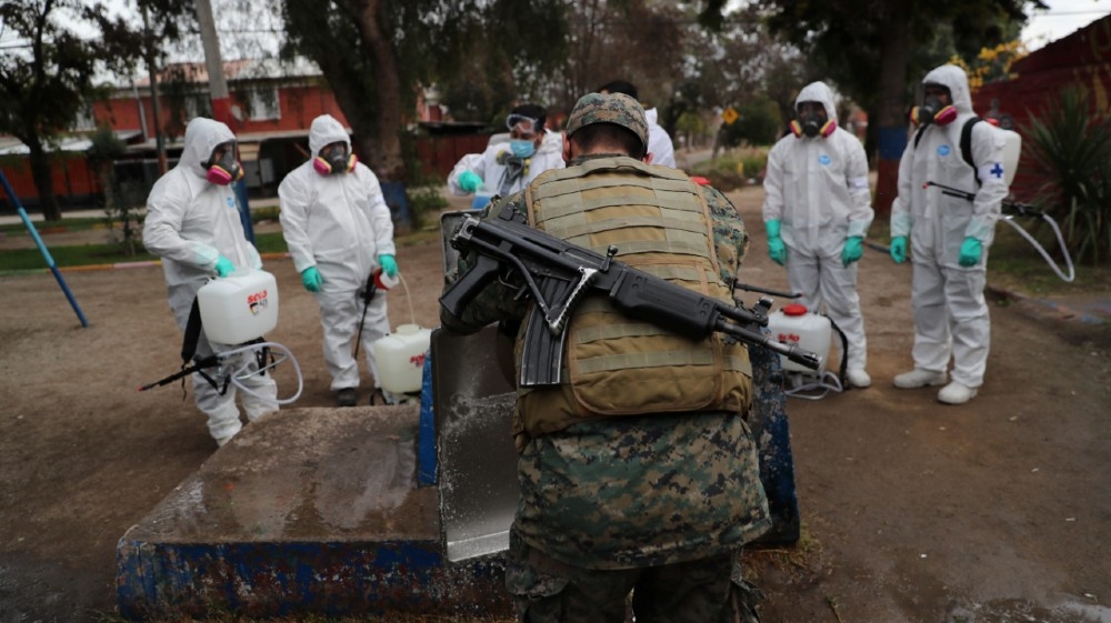 An army member washes a tray as comrades get ready to apply disinfectant before a food delivery in a socially vulnerable community following the outbreak of the coronavirus disease 