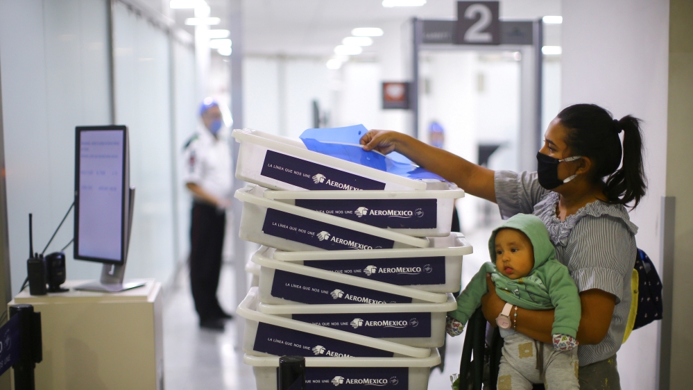 A passenger, wearing a protective mask, and her baby pass on a passenger checkpoint at the almost empty Benito Juarez international airport, as the spread of the coronavirus disease (COVID-19) continues in Mexico City, Mexico