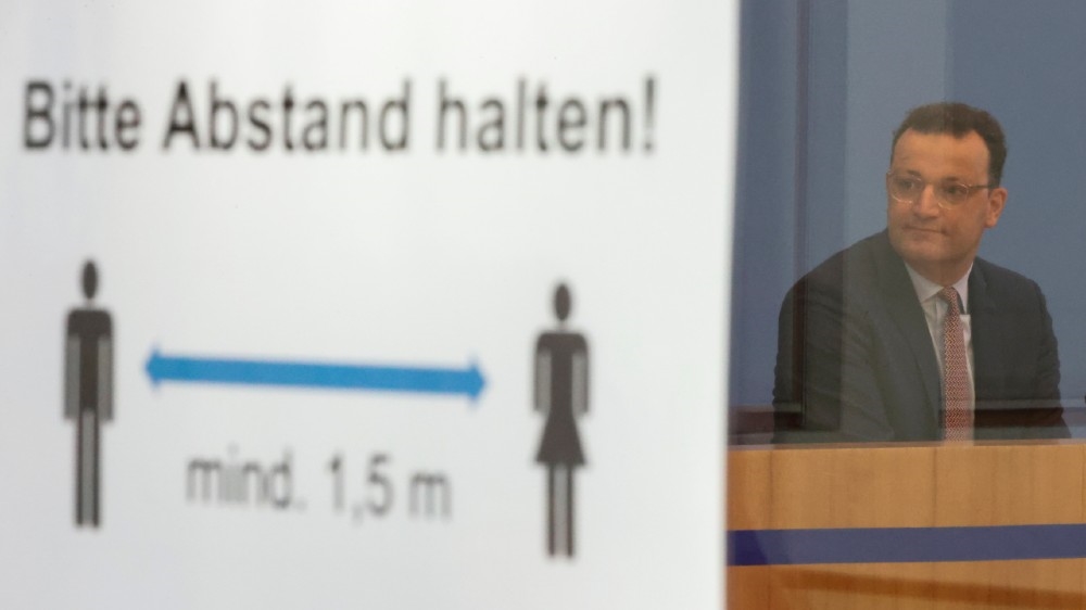German Health Minister Jens Spahn is seen next to a social distancing sign reading