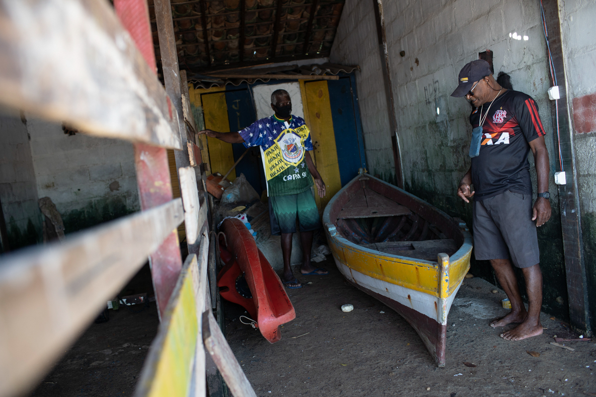 Fisherman Miguel Conceicao de Oliveira, 71, right, who recovered from COVID-19, talks with a friend at the Rasa “Quilombo” in Buzios, Brazil, Sunday, July 12, 2020. Miguel’s 78-year-old sister, Cariva