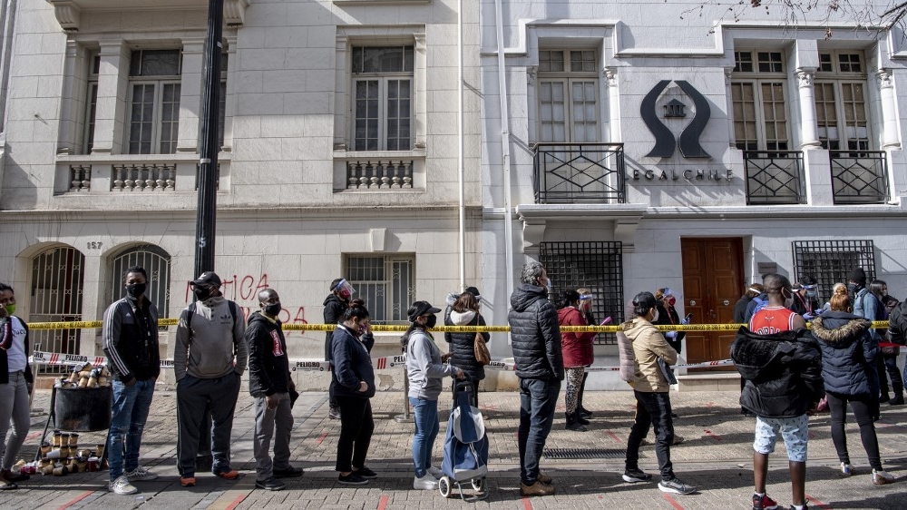 People wear face masks while queueing to enter a branch of the pension funds office to start the procedure to withdraw up to 10 percent of their deposits in Santiago, on July 30, 2020