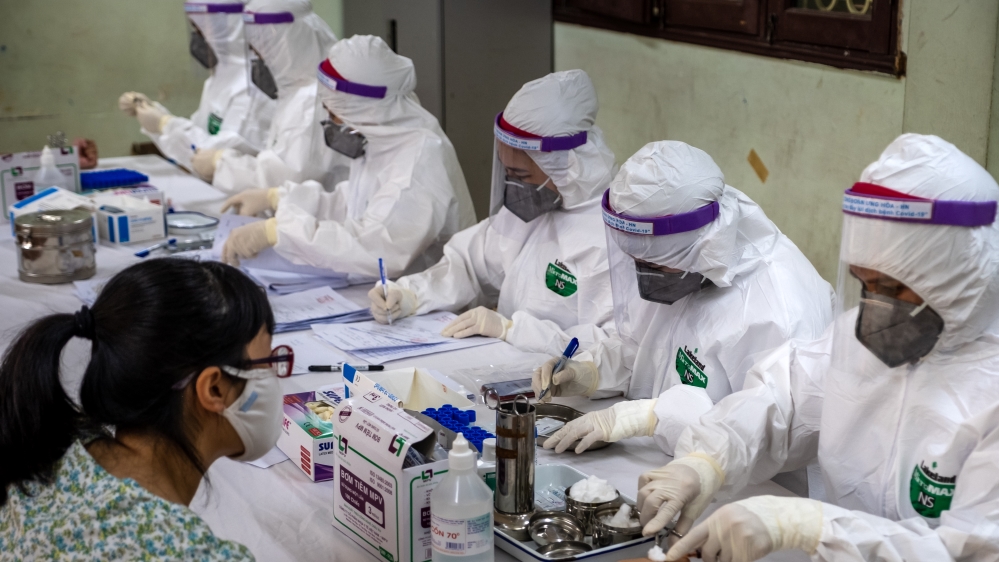 Medical specialists in protective suits collect blood samples for a COVID-19 rapid test from people who recently returned from Da Nang City on July 31, 2020 in Hanoi, Vietnam