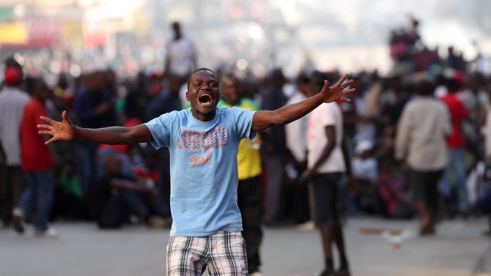 Supporters of the opposition Movement for Democratic Change react as soldiers prepare to disperse crowds outside the party's headquarters in Harare
