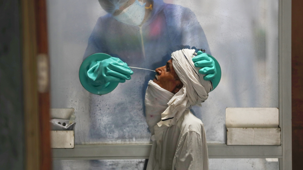 A health worker takes a nasal swab of a person for a COVID-19 test at a hospital in New Delhi, India, Monday, July 6, 2020. India has overtaken Russia to become the third worst-affected nation by the