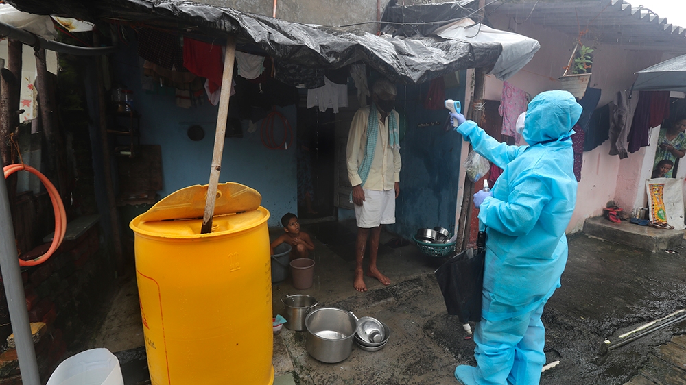 A health worker screens people for COVID-19 symptoms at a slum in Mumbai