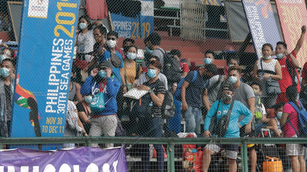People wearing face masks wait to have their coronavirus rapid tests at a stadium in Manila, Philippines