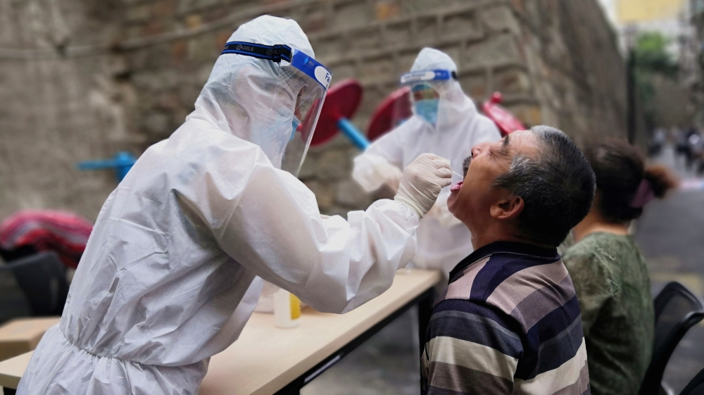 Medical worker collects swab from a man to conduct free nucleic acid tests for residents in the residential compound in Urumqi