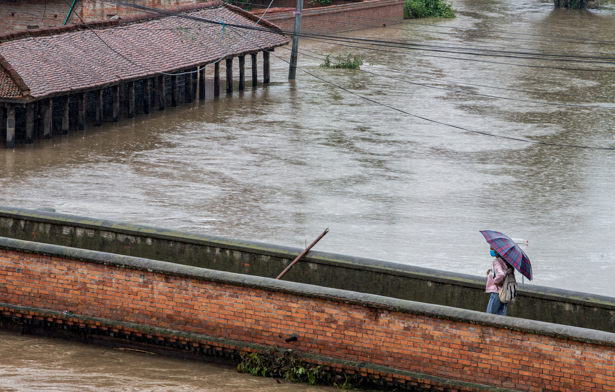 epa08558007 A young girl walks under an umbrella as a heavy rainfall floods Bhaktapur, Nepal, 21 July 2020. Meteorologists warned of heavy monsoon rains in Nepal that put several parts of the country