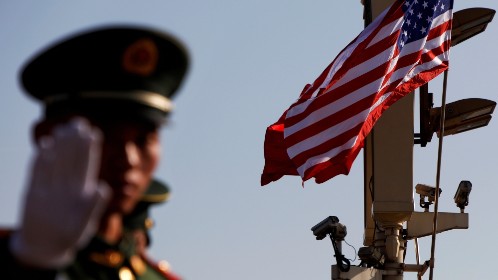 FILE PHOTO: A paramilitary policeman gestures under a pole with security cameras, U.S. and China''s flags, near the Forbidden City, ahead of a visit by U.S. President Donald Trump to Beijing
