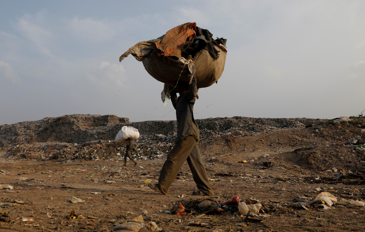 Mansoor Khan, 44, a waste collector, walks as he carries a sack of recyclable material after finishing work for the day at a landfill site, during the coronavirus disease (COVID-19) outbreak, in New D