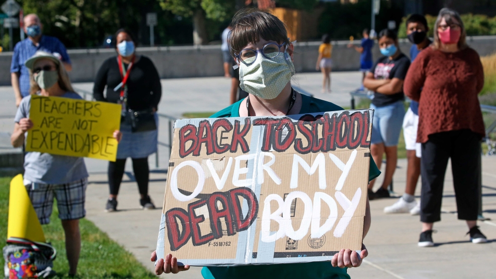A high school teacher holding a sign during a protest calling for schools to enforce mask-wearing and to implement other safety measures in advance of schools reopening in Salt Lake City, Utah