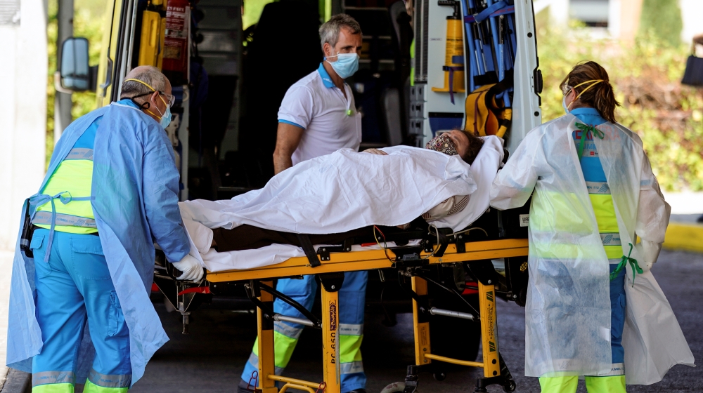 Healthcare workers wearing protective gears push a patient on a stretcher into the emergency unit at Severo Ochoa hospital, amid the outbreak of the coronavirus disease (COVID-19) in Leganes, Spain, A
