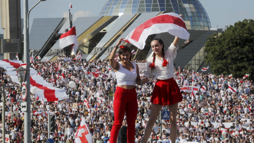 Two women wave an old Belarusian national flag during opposition rally in the center of Minsk, Belarus, Sunday, Aug. 16, 2020.