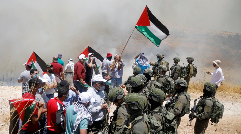 Palestinian demonstrators gather in front of Israeli forces during a protest against Israel's plan to annex parts of the occupied West Bank, Asira ash-Shamaliya near Nablus July 3, 2020. REUTERS/Rane