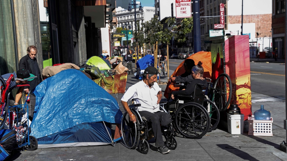People line in a sidewalk filled with tents set up by the homeless, amid an outbreak of the coronavirus disease (COVID-19), in the Tenderloin district of San Francisco,