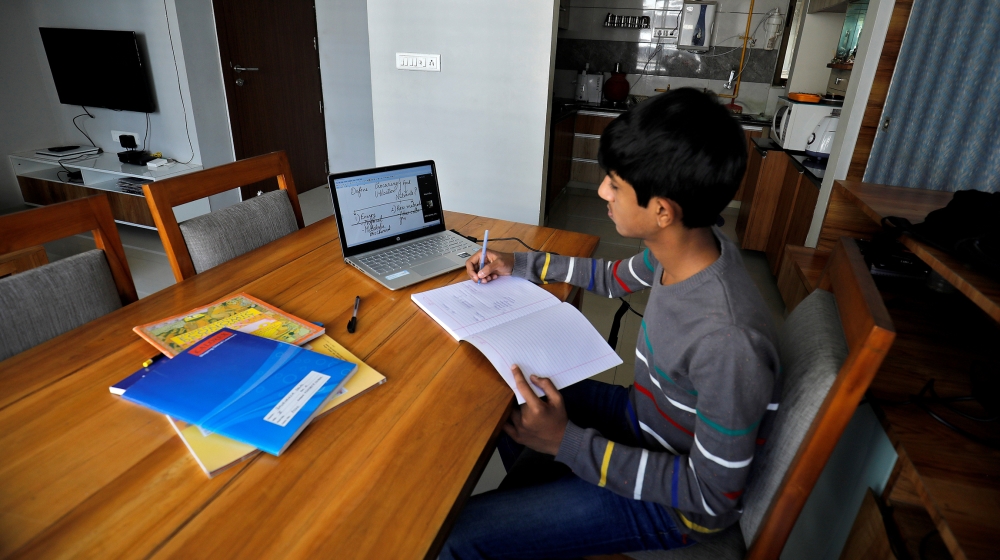 A student makes notes as he attends an online class at his home after Gujarat government ordered the closure of schools and colleges across the state amid coronavirus disease (COVID-19) fears, in Ahme