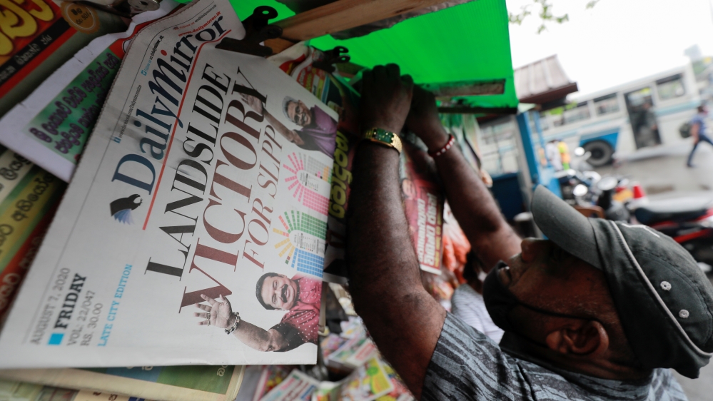 A man hangs newspapers carrying headlines about the victory of Mahinda Rajapaksa's Sri Lanka People's Front party in the country's parliamentary election in Colombo