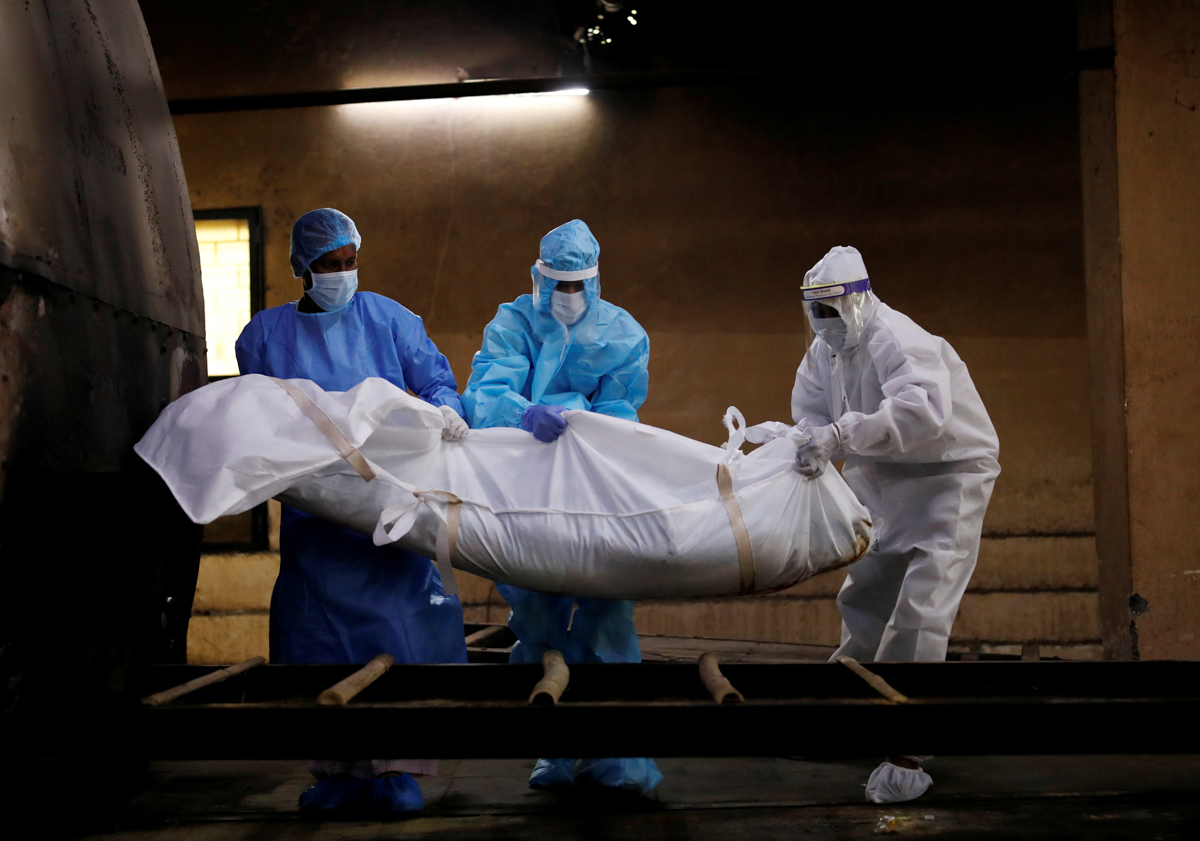 A health worker and relatives wearing personal protective equipment (PPE) carry the body of a man, who died due to the coronavirus disease (COVID-19), for his cremation, at a crematorium in New Delhi,