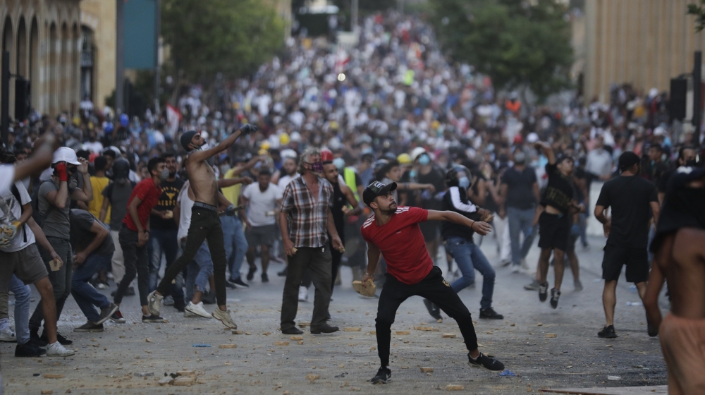 People throw stones during anti-government protest following Tuesday's massive explosion which devastated Beirut, Lebanon, Sunday, Aug. 9. 2020. (AP Photo/Hassan Ammar)