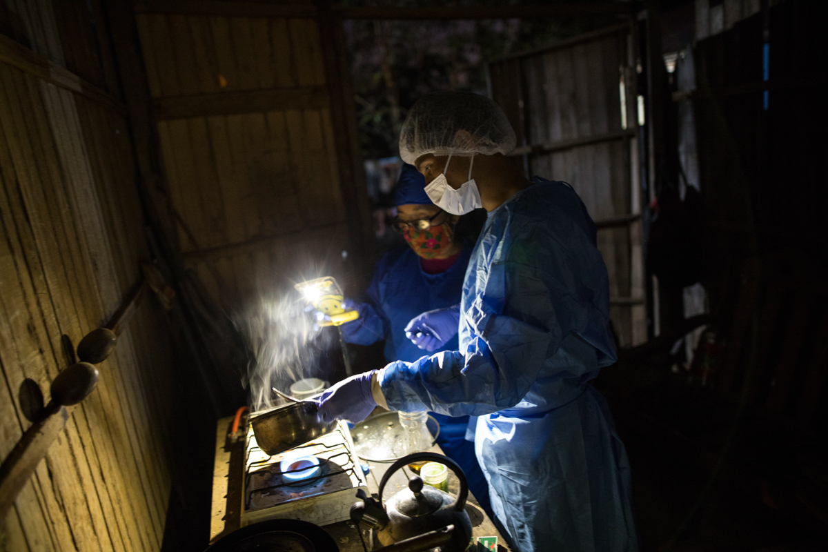 Comando Matico volunteers Mery Fasabi, left, and Isai Eliaquin Sanancino, heat an herbal remedy for a neighbor who has been suffering from COVID-19 symptoms, in the Shipibo Indigenous community of Puc