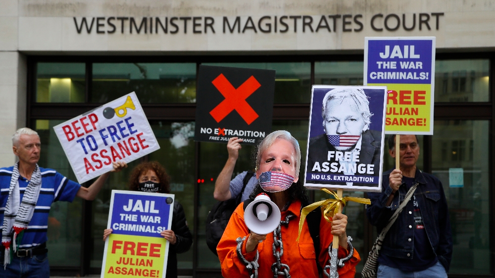 Demonstrators hold banners outside Westminster Magistrates Court in London, Friday, Aug. 14, 2020. A final procedural hearing in the Julian Assange extradition case will take place at the court