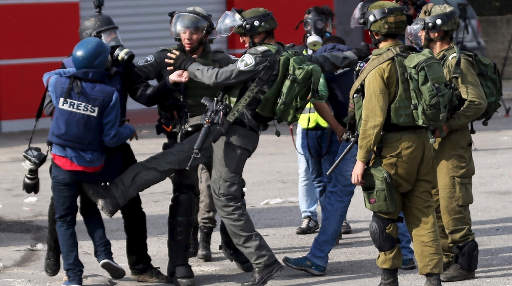 An Israeli border policeman kicks a Palestinian photojournalist during clashes with Palestinian protesters near the Jewish settlement of Bet El, near the West Bank city of Ramallah October 30, 2015. K