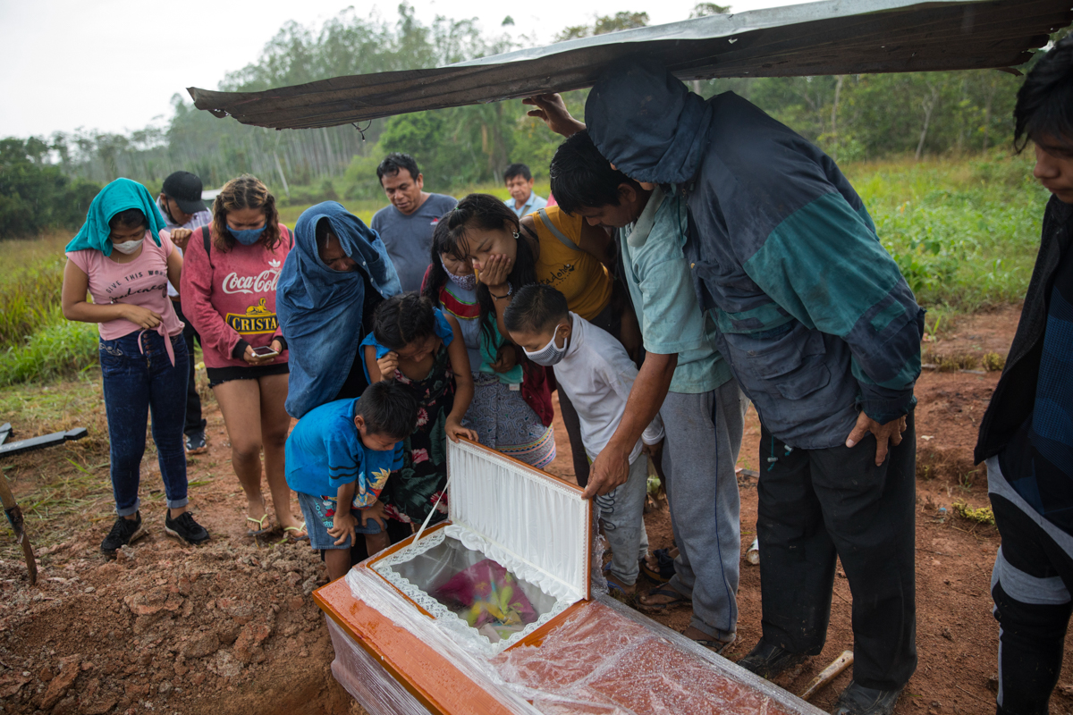 Family members look in the coffin that contains the remains of Manuela Chavez who died from symptoms related to the new coronavirus at the age of 88, during a burial service in the Shipibo Indigenous
